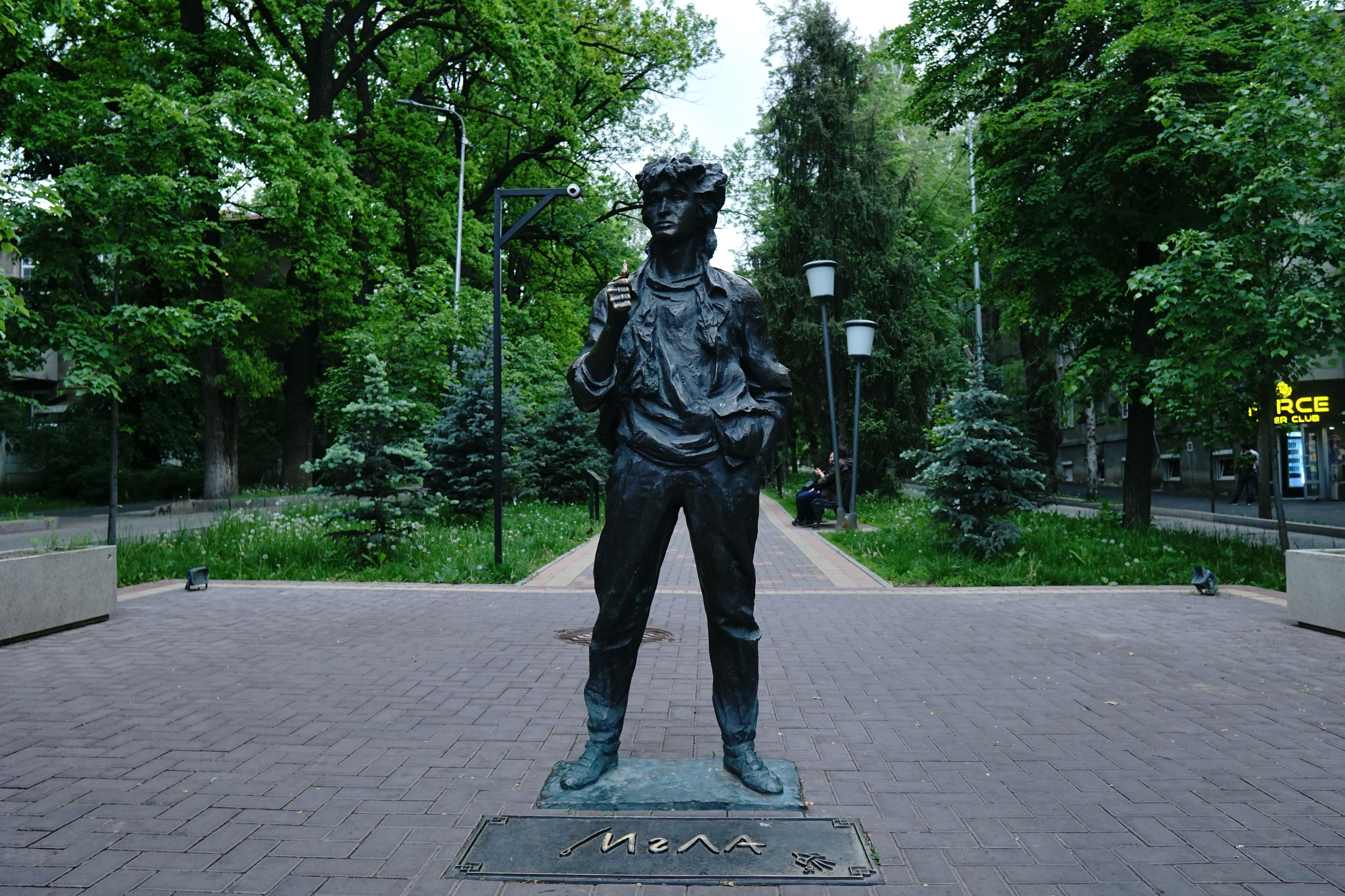 Bronze statue of a rock musician in a green park setting in Kazakhstan.