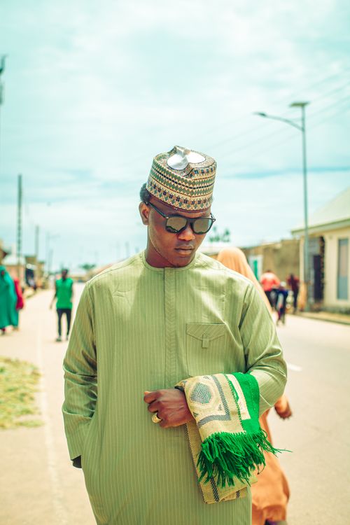 Free Man walking down a sunny street in traditional African outfit with sunglasses. Stock Photo