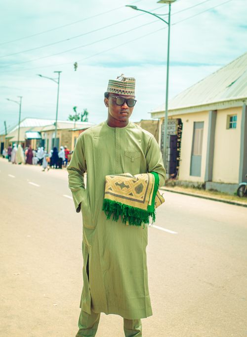 Free A young man wearing traditional attire walks confidently down a sunny street. Stock Photo