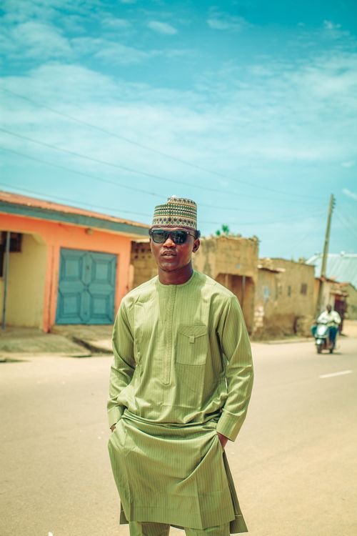 Free Man in traditional attire poses confidently on a sunny day, showcasing cultural fashion. Stock Photo