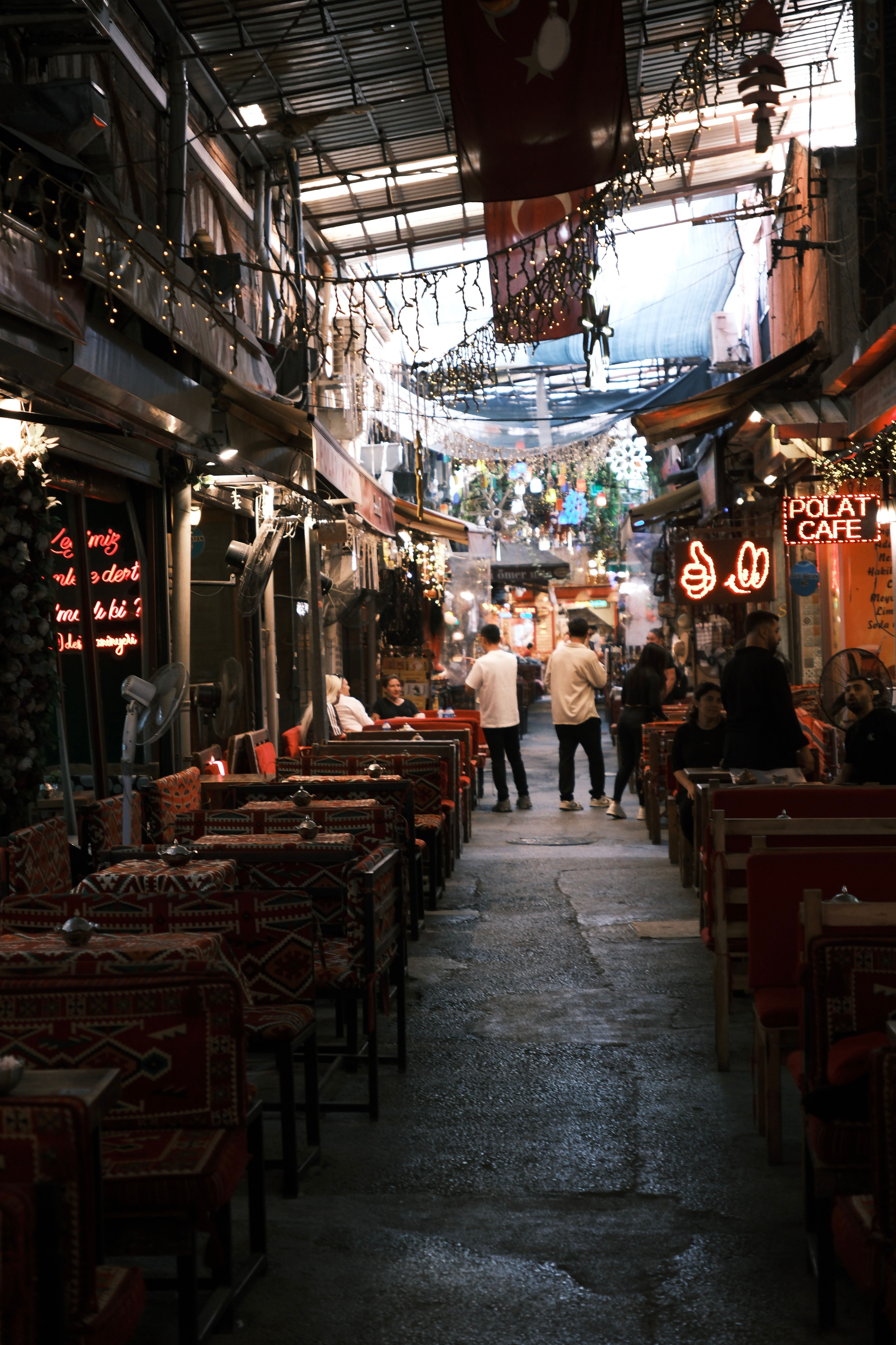 A vibrant indoor alley cafe with seating and decor, capturing the ambiance of İzmir's local culture.