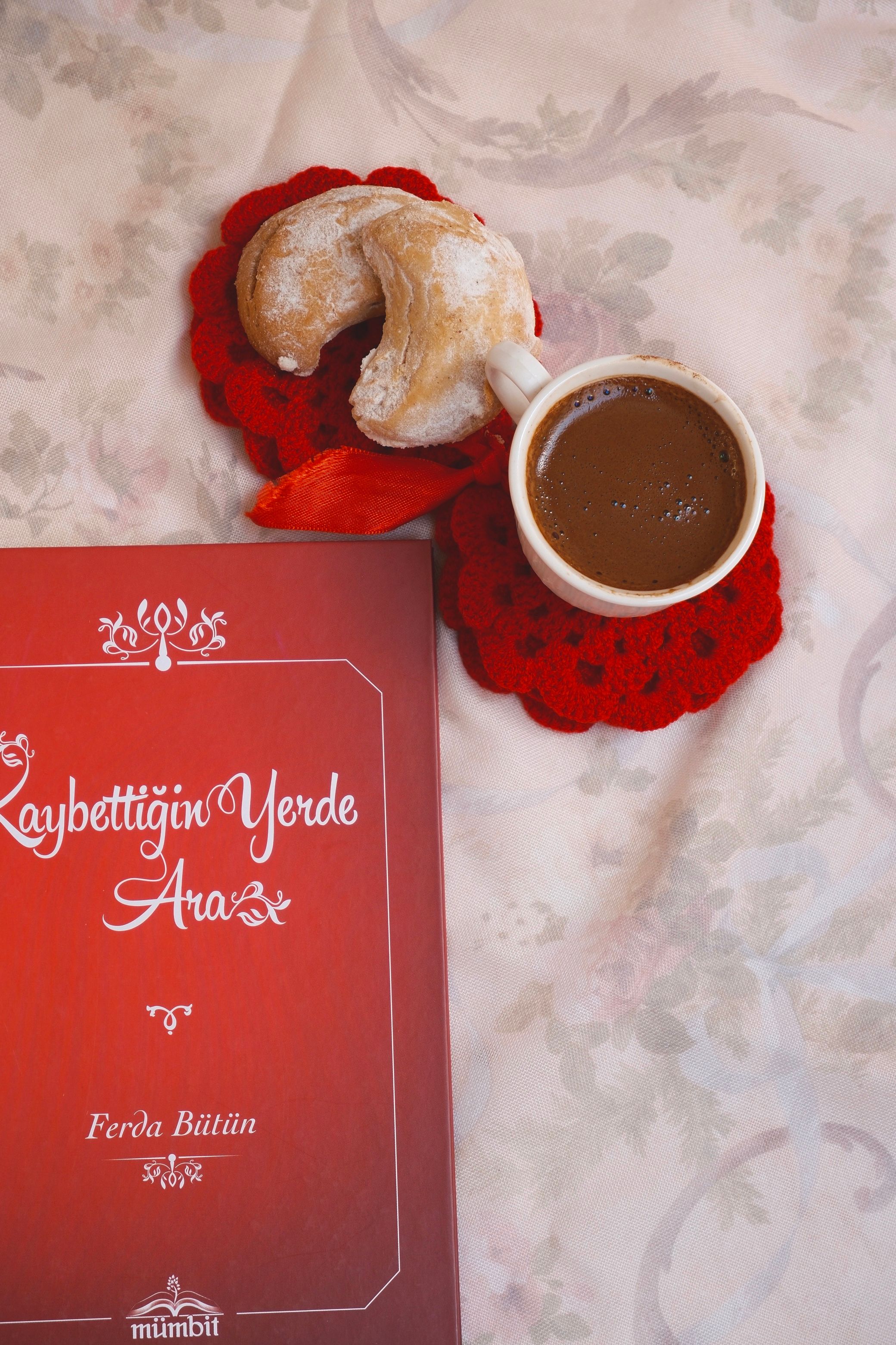 A warm cup of coffee with croissant and book on a cozy table setting.