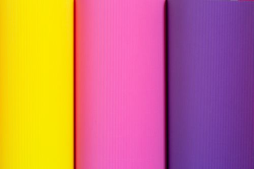 Free A minimalist abstract image featuring vibrant yellow, pink, and purple textile patterns with vertical ridges. Stock Photo
