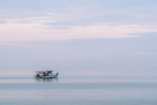 A serene image of a fishing boat on a tranquil sea with a pastel sky, captured during twilight.