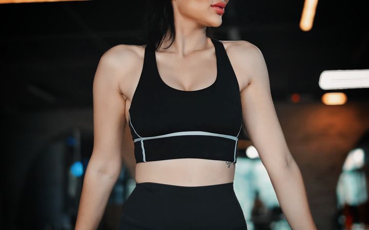Woman in athletic wear exercising in a gym with contemporary lighting.