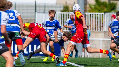 Free Energetic youth rugby match showcasing diverse players in action on a sunny day outdoors. Stock Photo