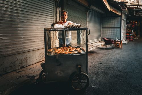 Free Man selling simit bread from a cart on a quiet street in İzmir, Türkiye. Stock Photo