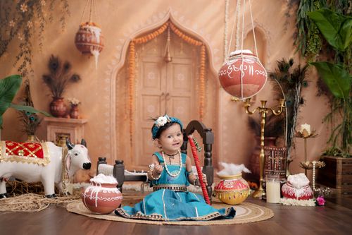 Free Charming baby in traditional Indian attire depicted as young Lord Krishna amidst cultural decor. Stock Photo