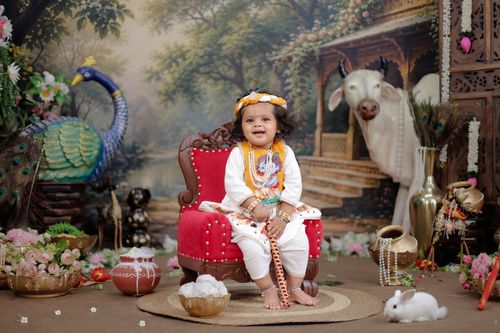 Free Adorable baby in traditional attire amidst colorful Indian cultural decor, with animals and floral arrangements. Stock Photo