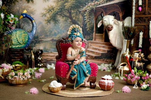 Free Adorable baby dressed as Hindu deity with colorful peacock and traditional decor. Stock Photo