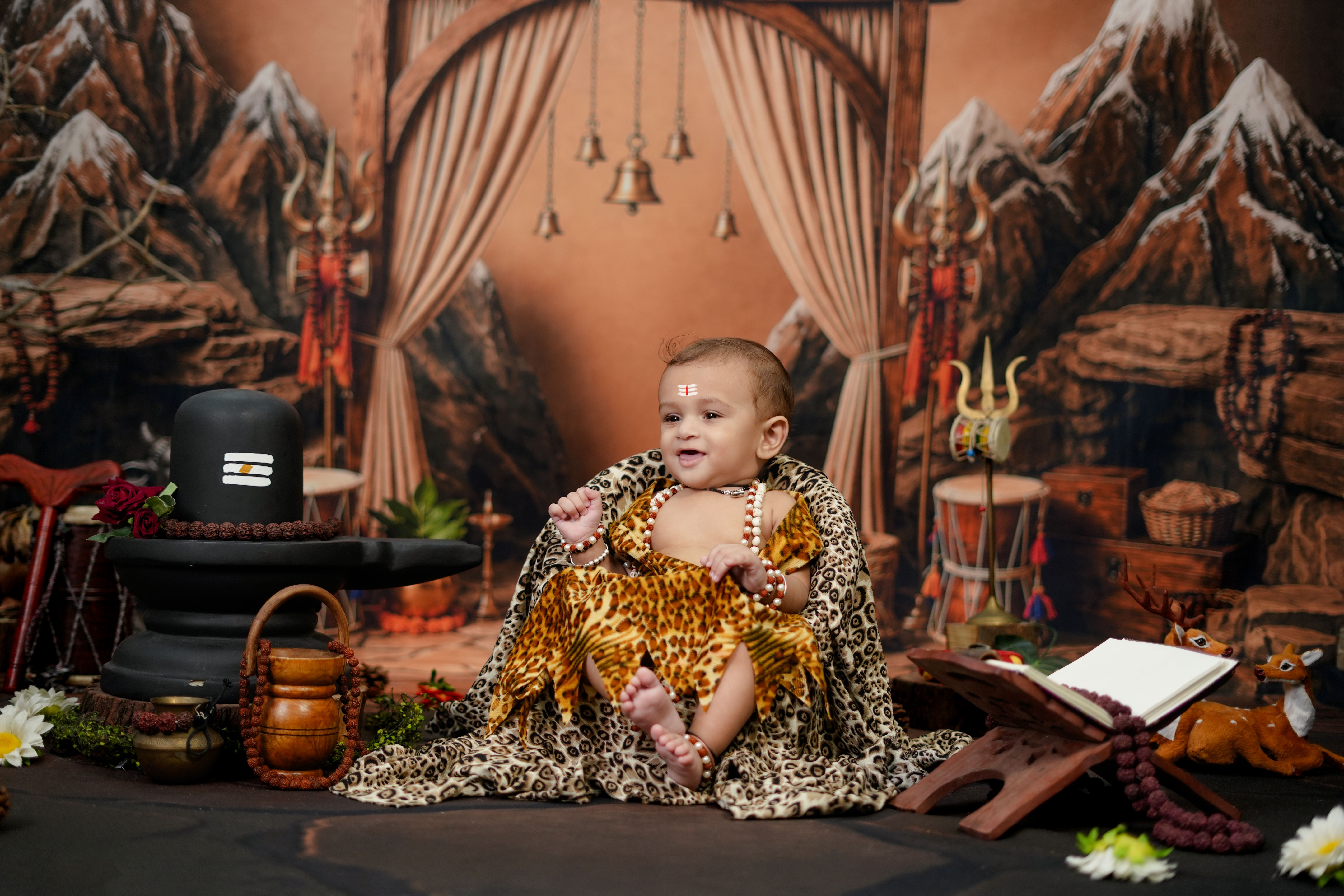 Adorable baby with traditional attire in a cultural Indian backdrop.