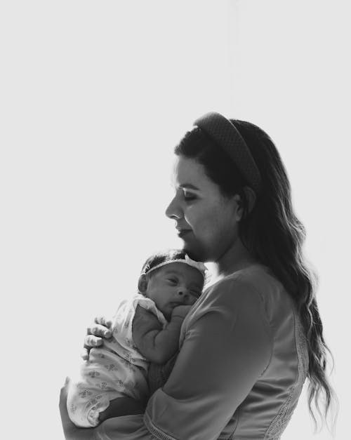 Grayscale Photo of Woman Carrying Baby