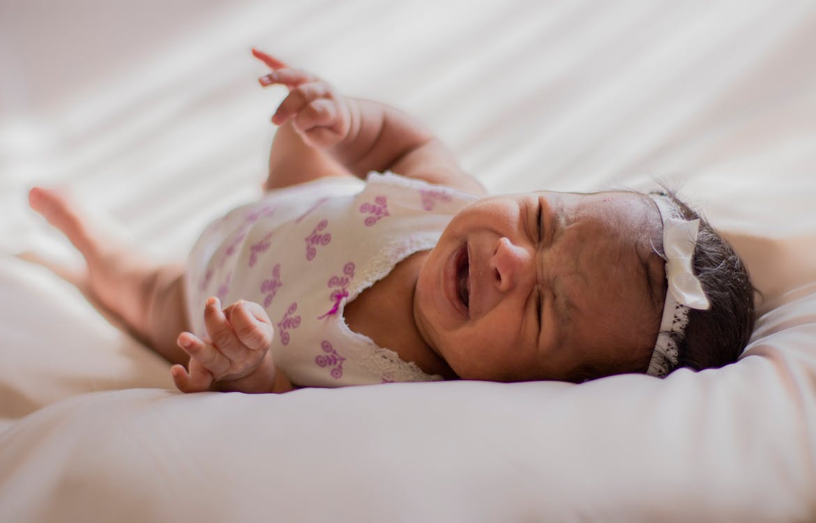 Free Baby In A Onesie Lying On Bed Stock Photo