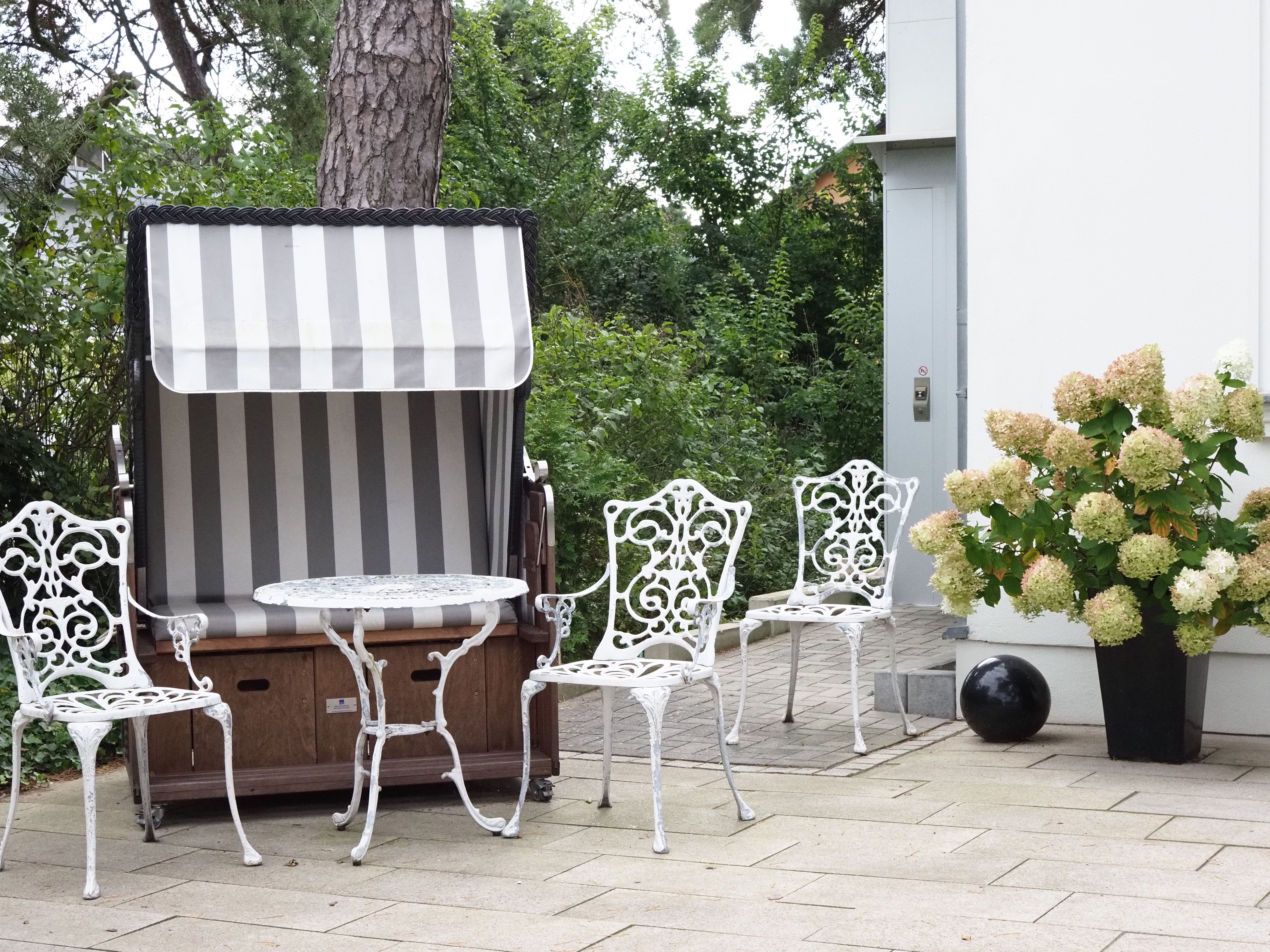 Elegante Sitzgruppe mit Vintage-Stühlen unter einem Baldachin in üppigem Garten