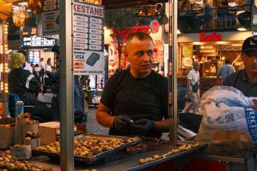 Free Night scene of a vibrant street market in Istanbul featuring a chestnut vendor and lively atmosphere. Stock Photo