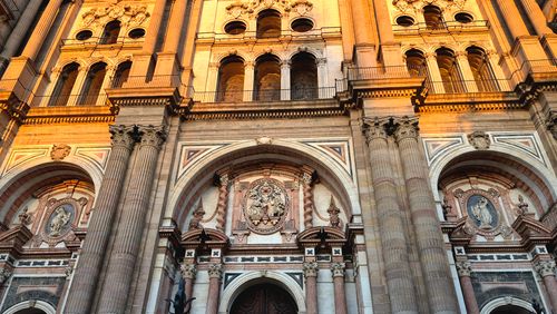 Free Close-up of the illuminated facade of Málaga Cathedral capturing its architectural grandeur at sunset. Stock Photo
