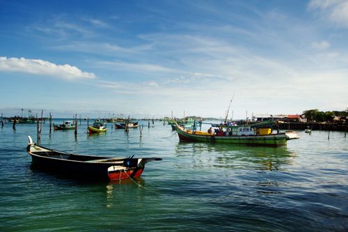 Free Colorful fishing boats anchored in a serene harbor under a clear blue sky. Stock Photo