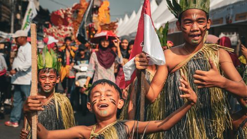 Free Children in traditional attire enjoying a vibrant cultural parade in Jakarta, Indonesia. Stock Photo