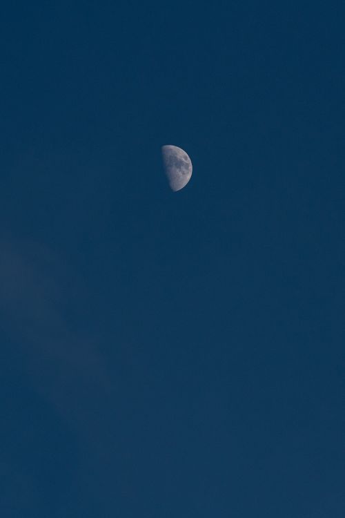 Free A serene view of a crescent moon set against a clear, deep blue night sky. Stock Photo