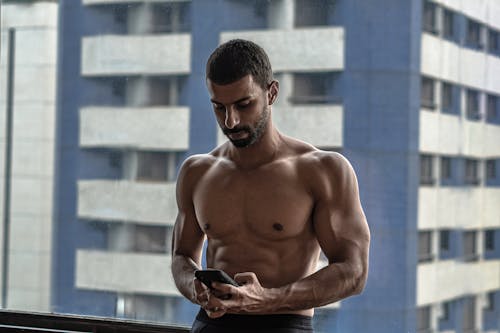 Topless Man Holding Black Smartphone