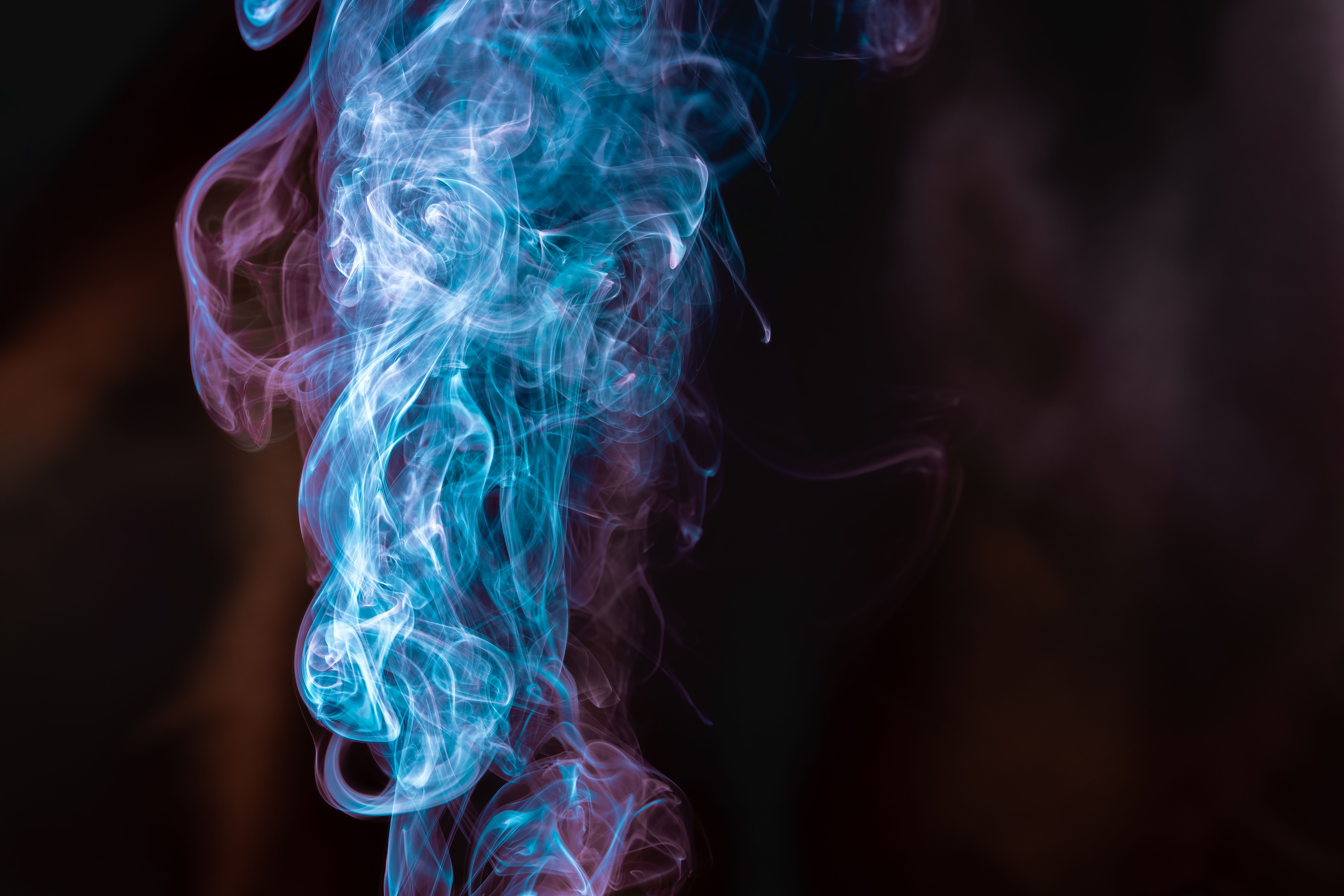 Vibrant blue and purple smoke swirls on a dark, neutral background.