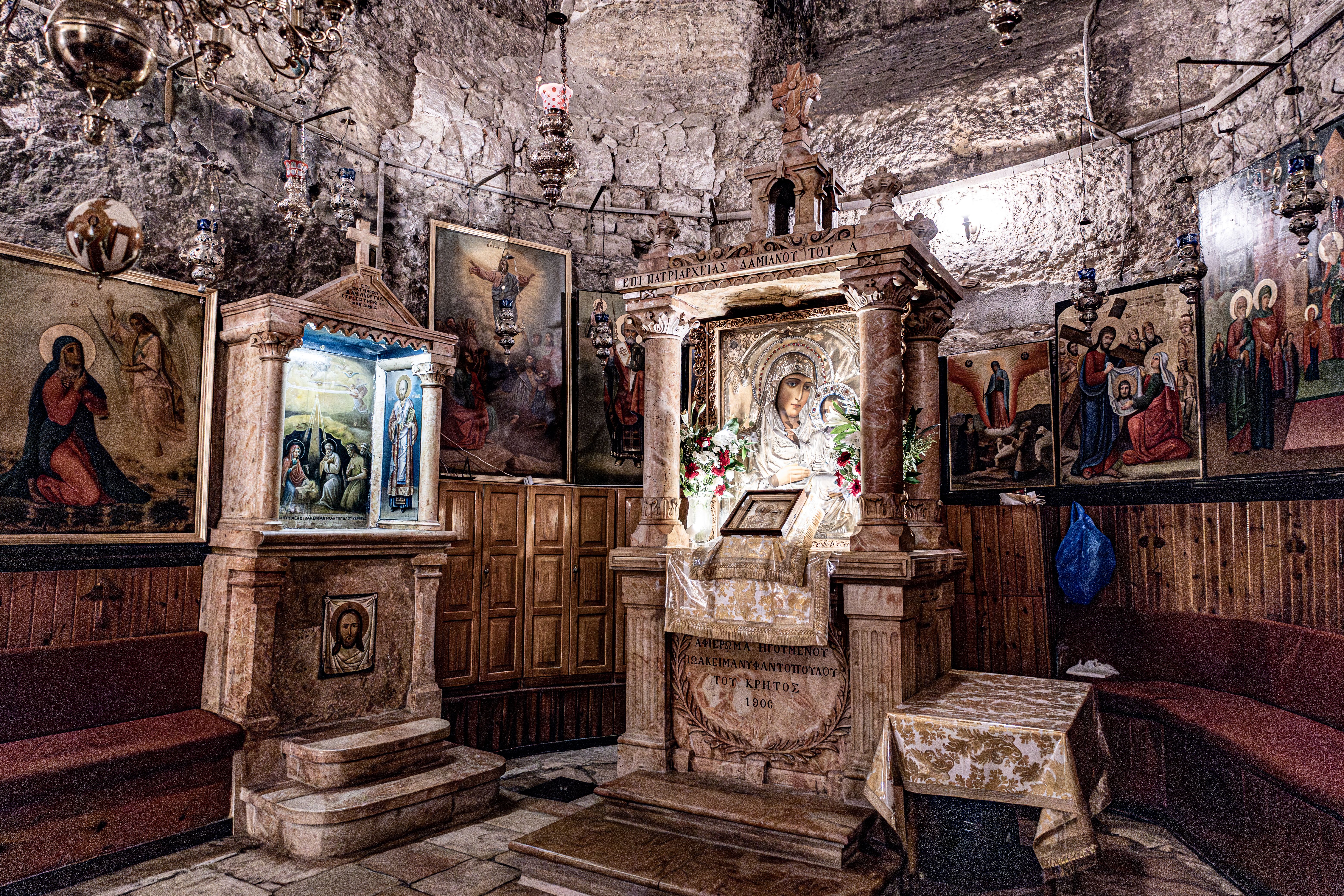 Intricate religious iconography inside a historic Jerusalem chapel featuring ornate altars and paintings.