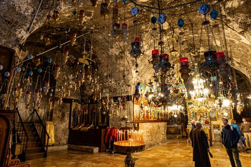 Free Interior of a historic church in Jerusalem with ornate chandeliers and lit candles. Stock Photo