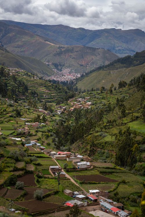 Free A breathtaking view of an Andean valley with terraced fields and distant mountains under cloudy skies. Stock Photo