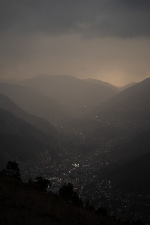 Free Aerial view of a small town nestled in misty mountains at dusk with lights glowing. Stock Photo