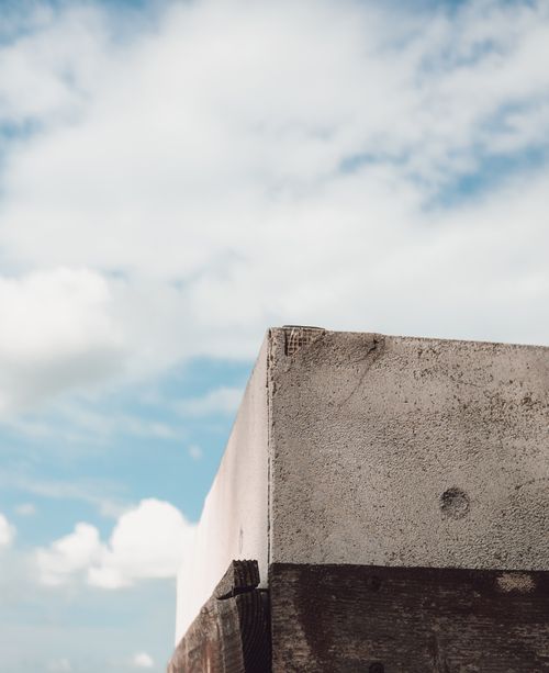 Free A minimalist photograph of a concrete structure set against a clear blue sky with clouds. Stock Photo