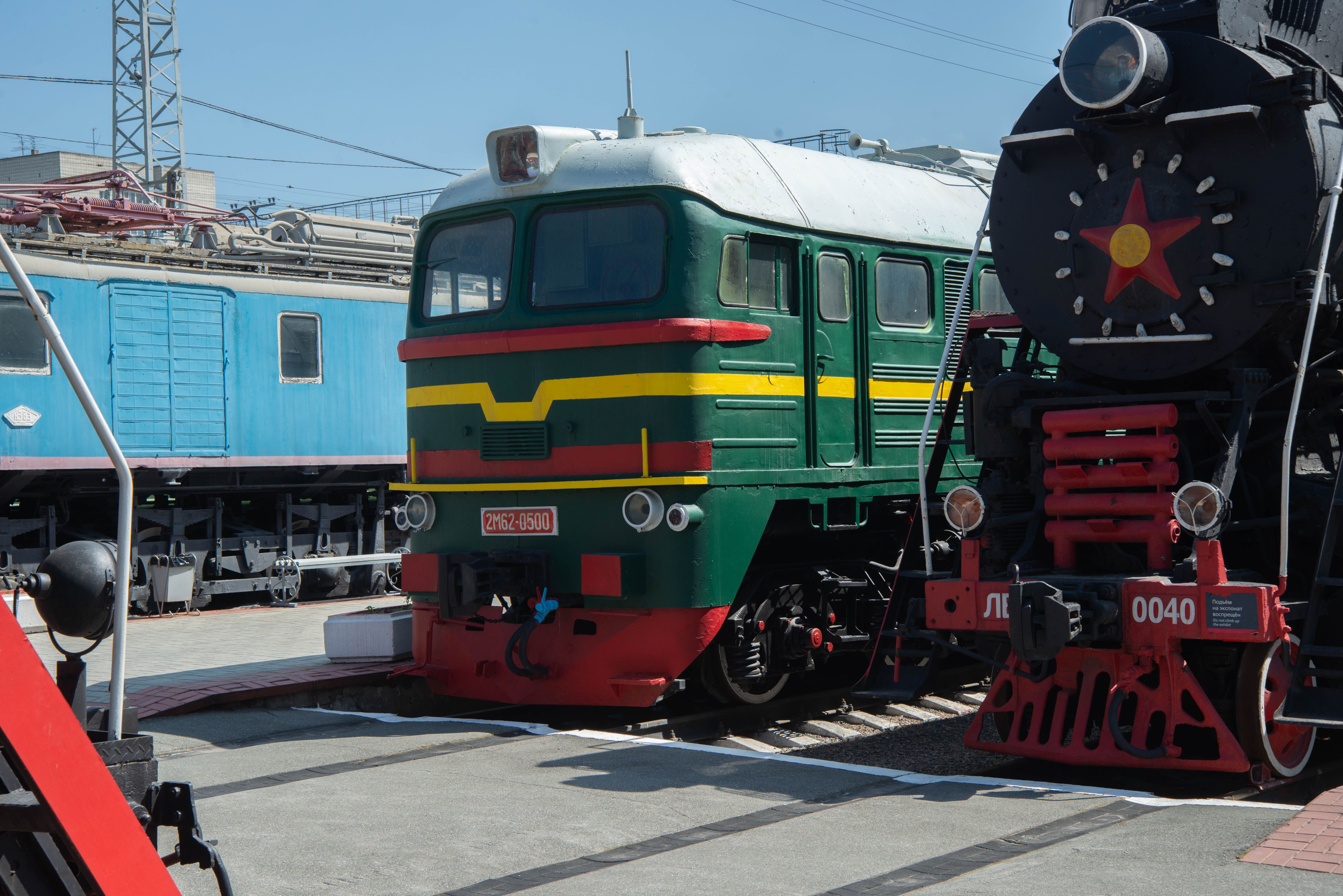 Colorful vintage trains displayed at an outdoor railway museum on a sunny day.