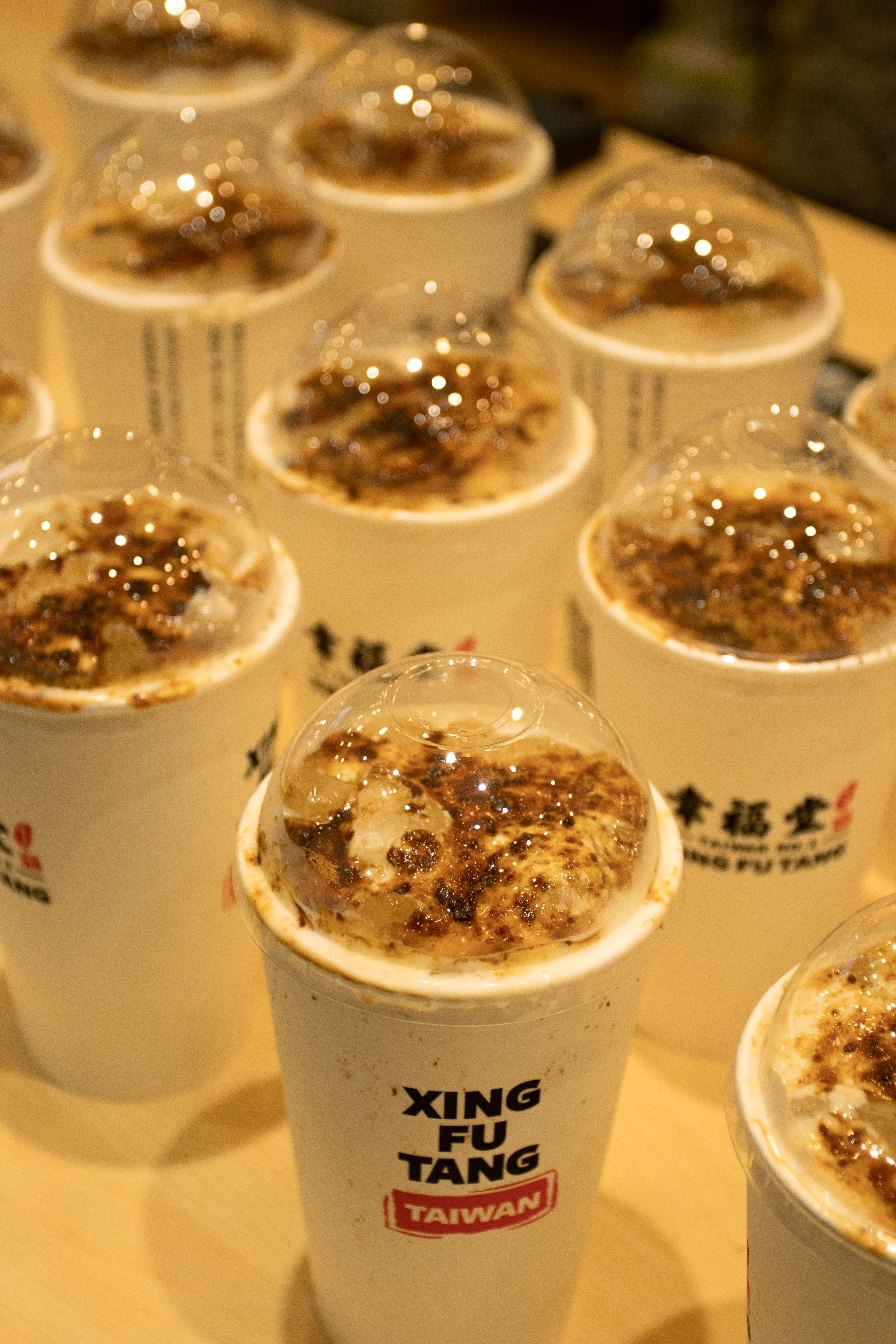 Close-up of Xing Fu Tang brown sugar milk tea cups with clear lids.