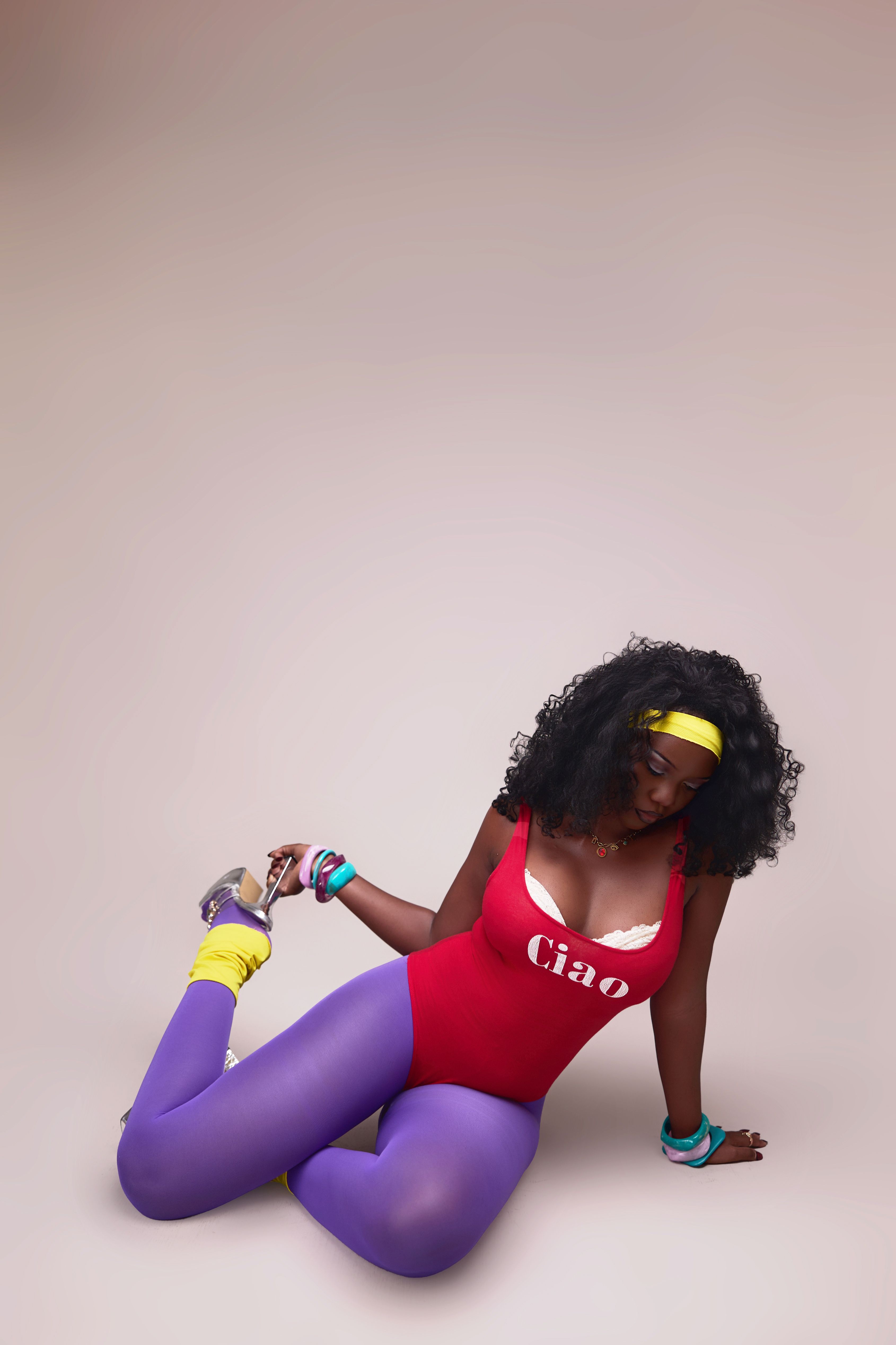 A woman in vibrant workout attire from the 80s with 'Ciao' text, striking a pose.