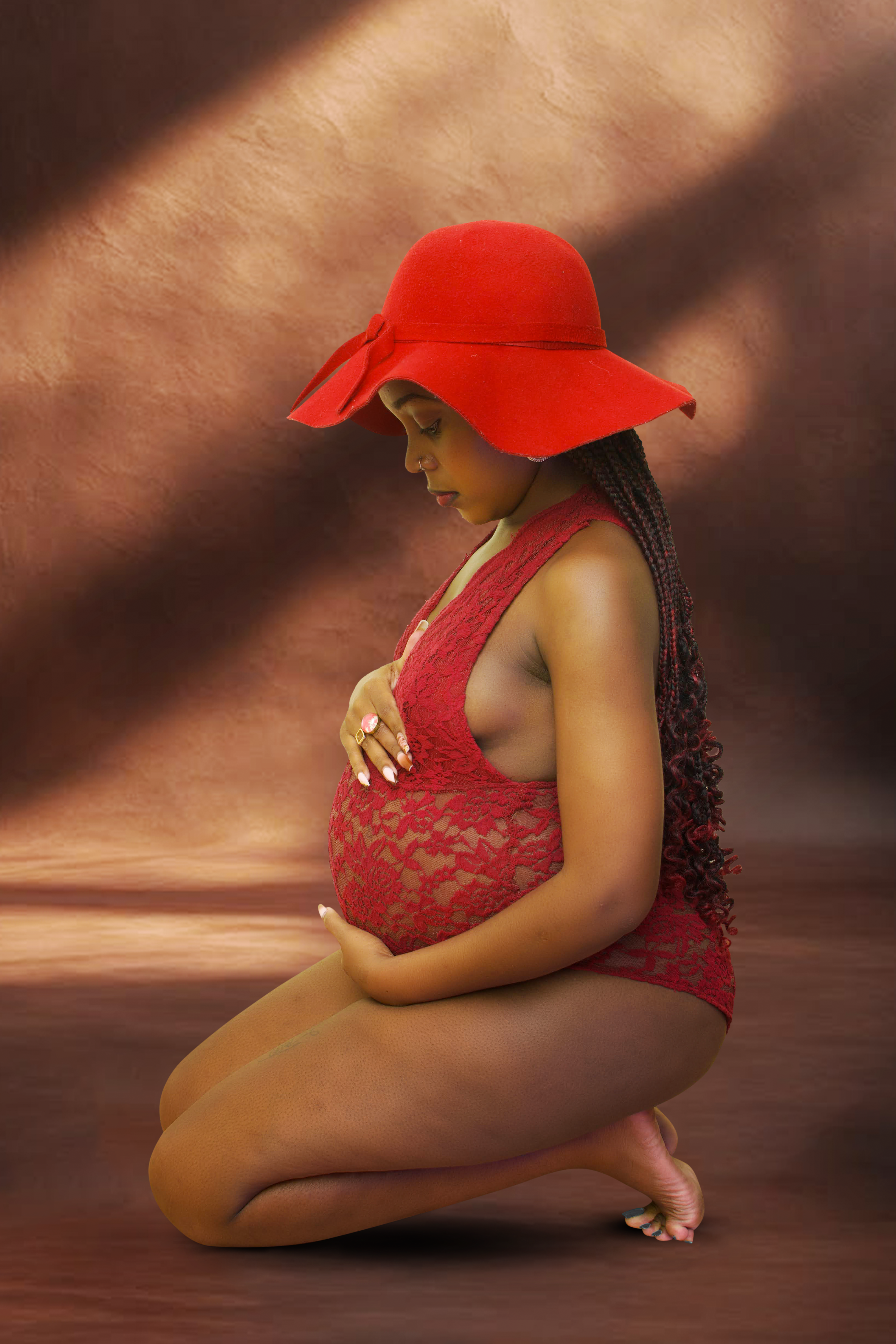 Pregnant woman in elegant lace attire posing gracefully indoors.