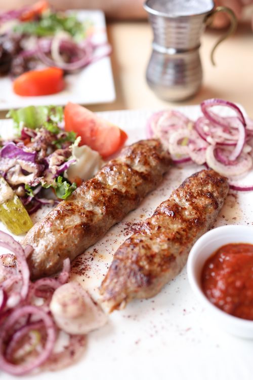 Free Juicy lamb kebabs served with fresh salad and spicy red sauce, perfect for lunch or dinner. Stock Photo
