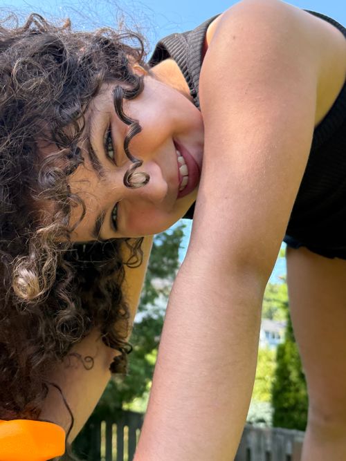 Free Smiling child with curly hair enjoying a playful outdoor moment on a sunny day Stock Photo