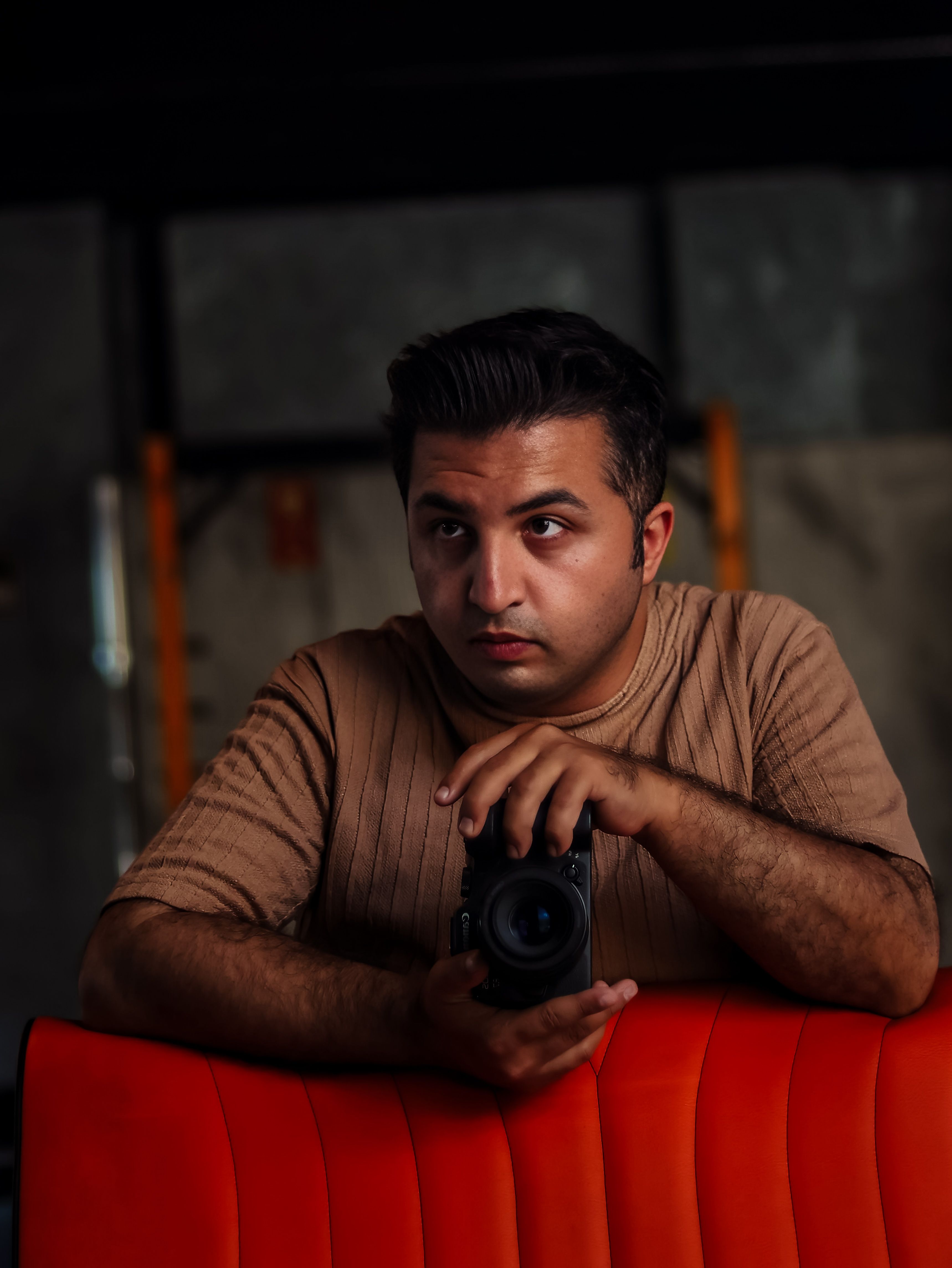 Portrait of a contemplative photographer holding a camera indoors.
