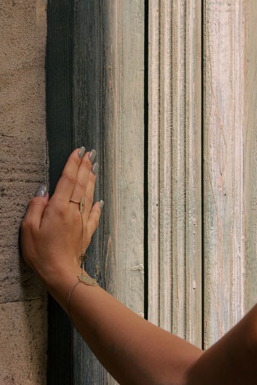 Free Close-up of a hand with jewelry touching an old textured door, evoking a sense of history and elegance. Stock Photo