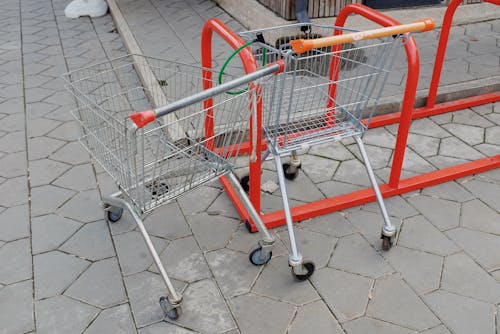 Shopping trolleys attached to metal stand near supermarket on street