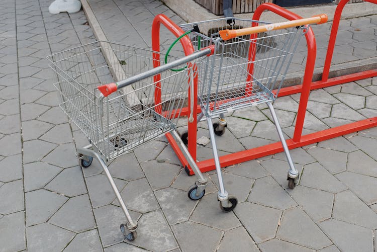 Shopping Trolleys Attached To Metal Stand Near Supermarket On Street