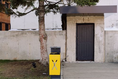 Free Yellow metal recycle urn placed under tree near entrance of building on street in city Stock Photo