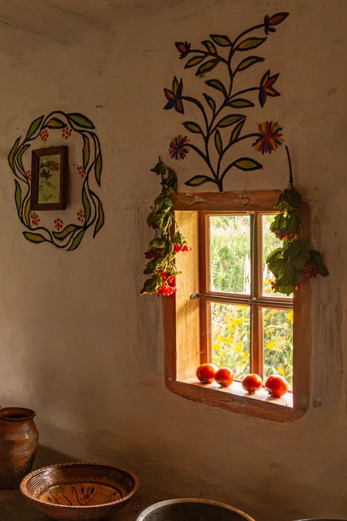 Free Warm Ukrainian interior showcasing traditional decor, pottery, and a sunlit window with tomatoes. Stock Photo