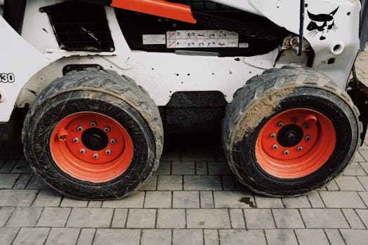 Detailed view of construction machinery wheels with red rims on a paved surface.