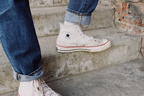 Person in Blue Denim Jeans Wearing White Converse  Sneakers