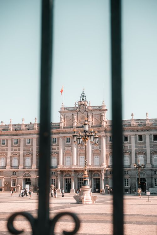 Free View of the Royal Palace of Madrid framed by wrought iron gate in a sunny courtyard. Stock Photo