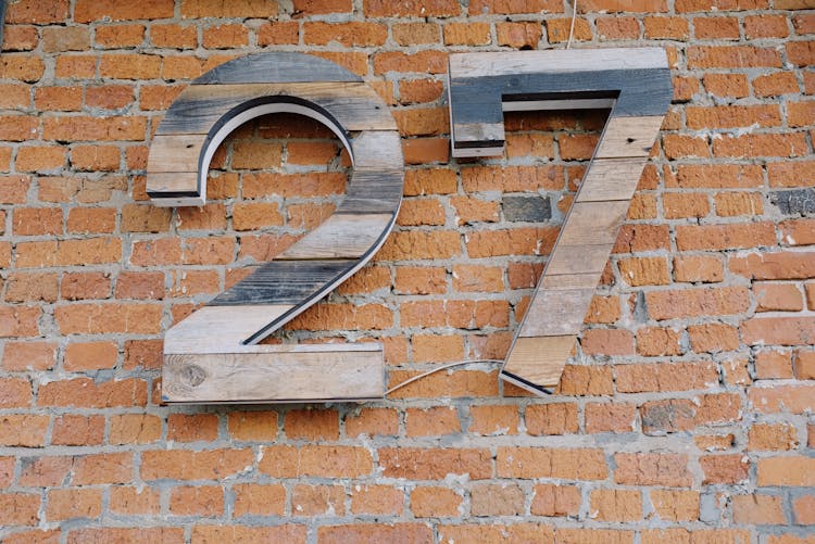 Big Wooden Number Sign Hanging On Brick Wall Of Modern Building