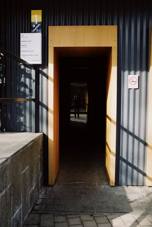 Free Entrance of modern building with black metal wall with wooden doorway on sunny street in city Stock Photo