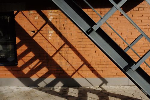 Free Metal staircase located near shabby brick wall of modern building in sunny day on street in city Stock Photo