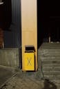 Yellow trash bin near wall of modern building