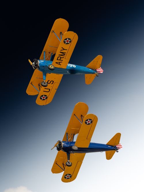 Free A pair of vintage U.S. Army Stearman biplanes flying against a clear sky, showcasing historical aviation. Stock Photo